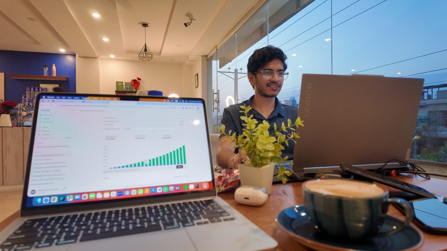 Waseem Nasir at a dual-laptop setup running an editing and analytics pipeline over coffee