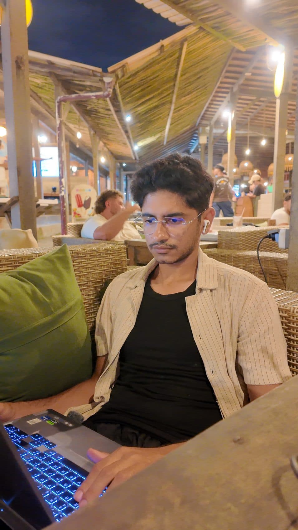 Waseem Nasir typing on a backlit laptop keyboard at a night cafe in Bali