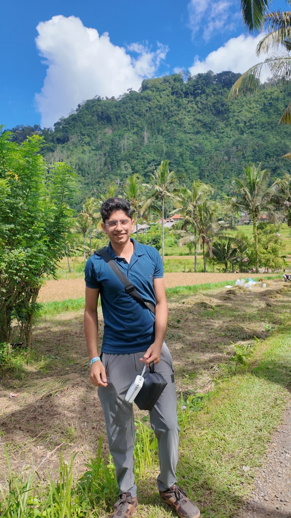 Smiling in a rice field framed by palms and mountains