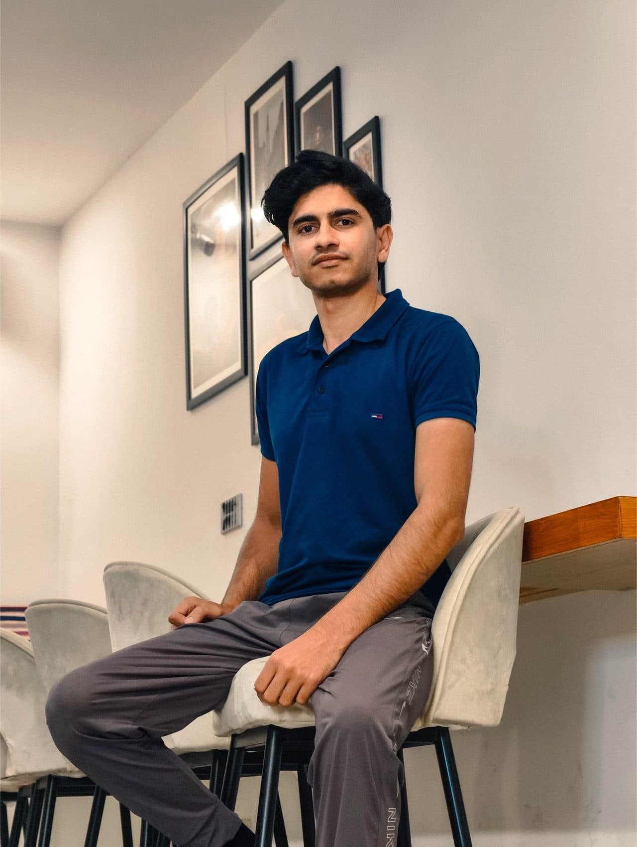 Seated portrait in a navy polo beside framed art